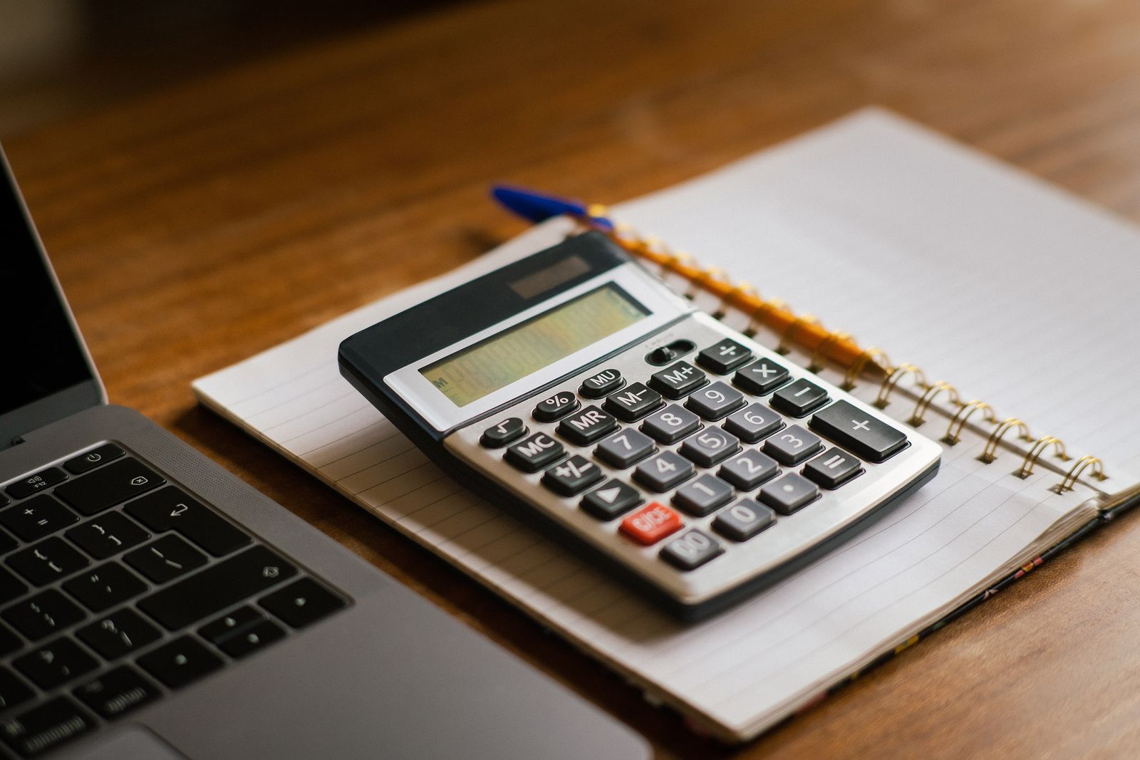 A calculator and notebook on a desk used to rebalance a monthly budget
