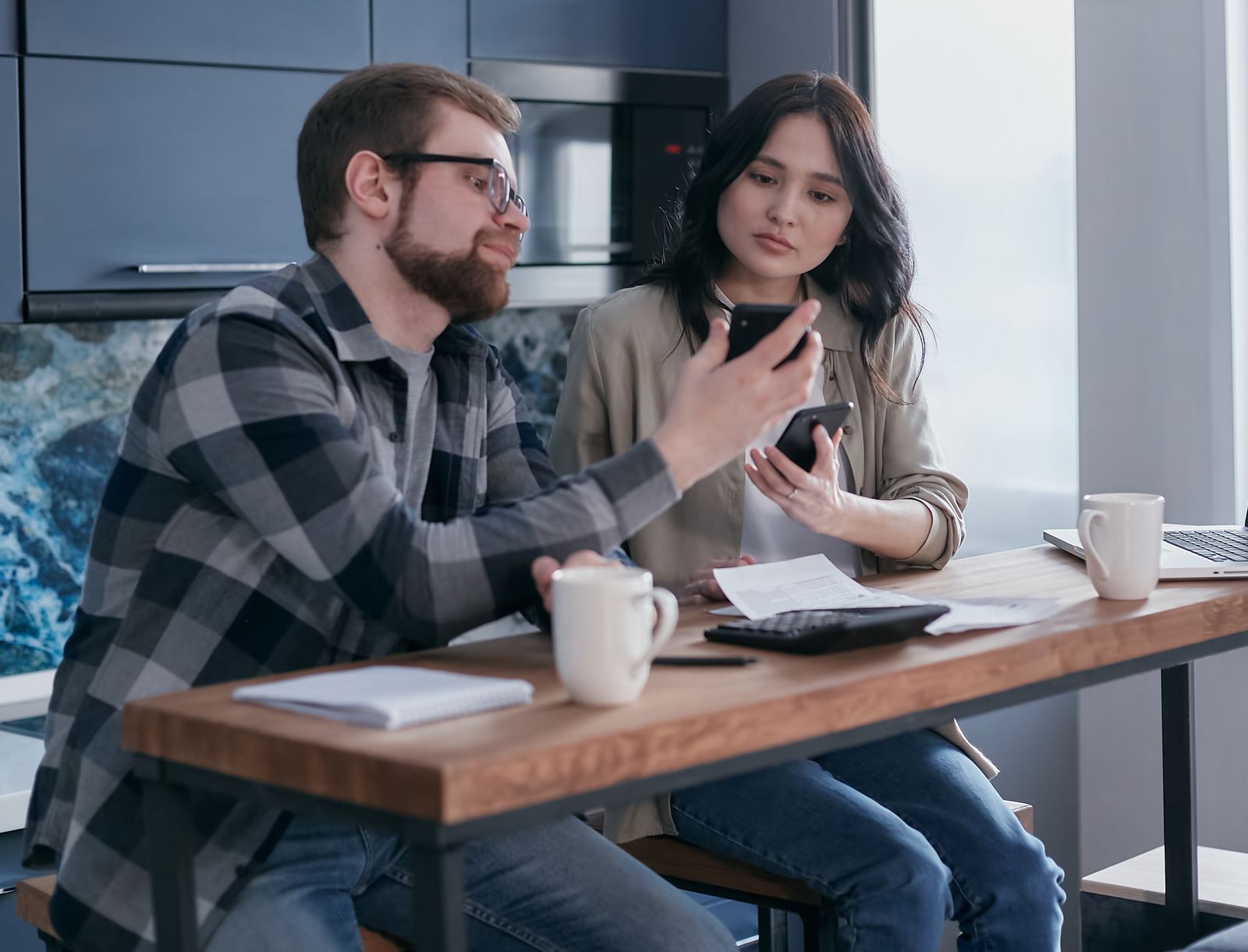 A person checking receipts and a bank app at a kitchen table to find where a budget went over