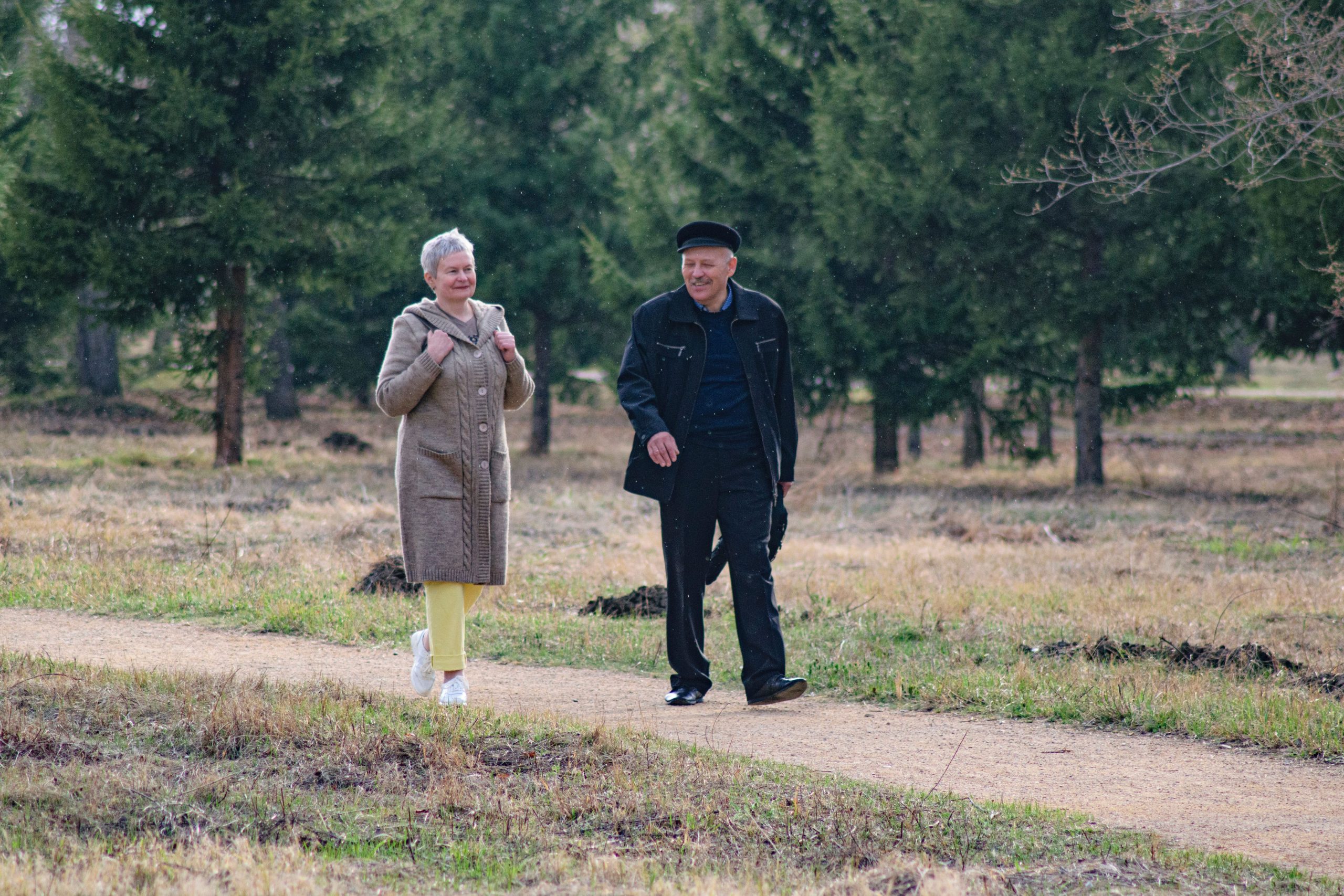An older couple walking outdoors together in a bright, calm setting
