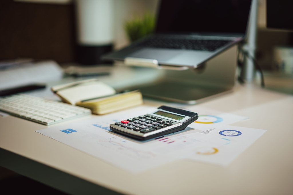 A modern desk with a laptop, calculator, and investment documents