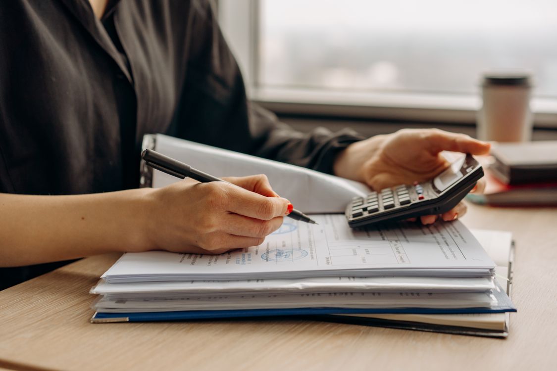 A real photograph of a person reviewing a loan statement with a calculator at a desk
