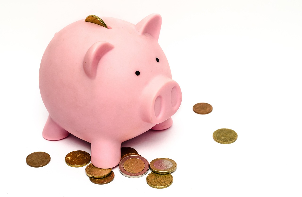 Pink piggy bank with coins on a white background